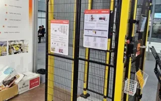 machine guard fencing front-facing close-up of yellow framed Mdfence safety gate with black mesh and exhibition demo cell