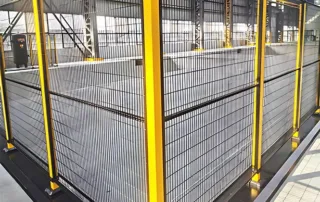 Herói industrial da cerca de segurança mostrando invólucro de malha preta para contenção de falhas de máquina em uma célula de usinagem propensa a falhas