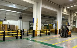Sistema di barriere di sicurezza per carrelli elevatori in magazzino con rotaie di protezione in acciaio giallo per colonne e aree di carico
