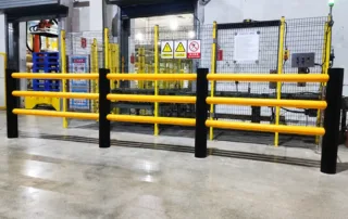 Barriera antiurto installata in un corridoio di fabbrica con guide tubolari gialle e montanti neri