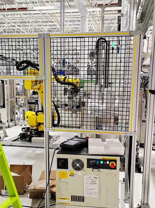 Aluminum safety fence for a robot cell with aluminum profiles, welded wire mesh panels, and guarded automation equipment