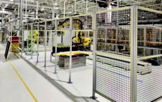 Machine guard fencing: Modular wire mesh machine guarding enclosure with anchored posts protecting a yellow robotic automation cell