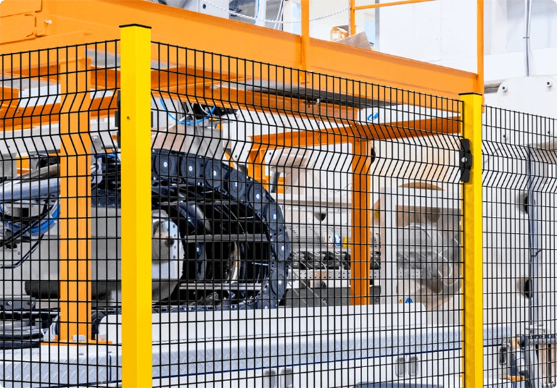 Safety fence industrial guarding automated machinery on a production line with yellow posts and welded mesh