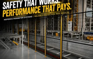 Industrial machine safety fencing with welded mesh panels, yellow posts, and bolted base plates in factory line