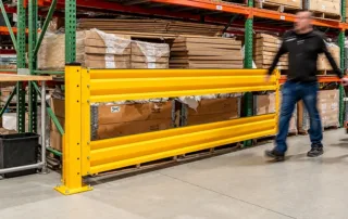 Thrie beam guardrail with dual corrugated rails, bolted base plates, and pallet racking protection