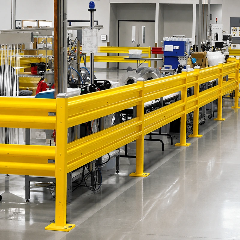 Steel guard rail with dual corrugated rails and floor-mounted posts separating factory machinery from pedestrian traffic