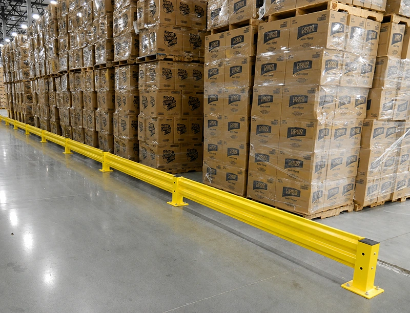 Safety barrier system with double-beam rails and bolted base plates protecting palletized inventory