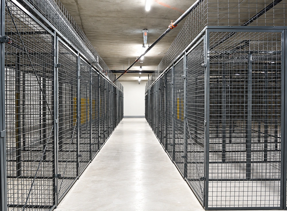 Industrial wire mesh storage cages forming a central aisle for secure warehouse partitioning and organization.
