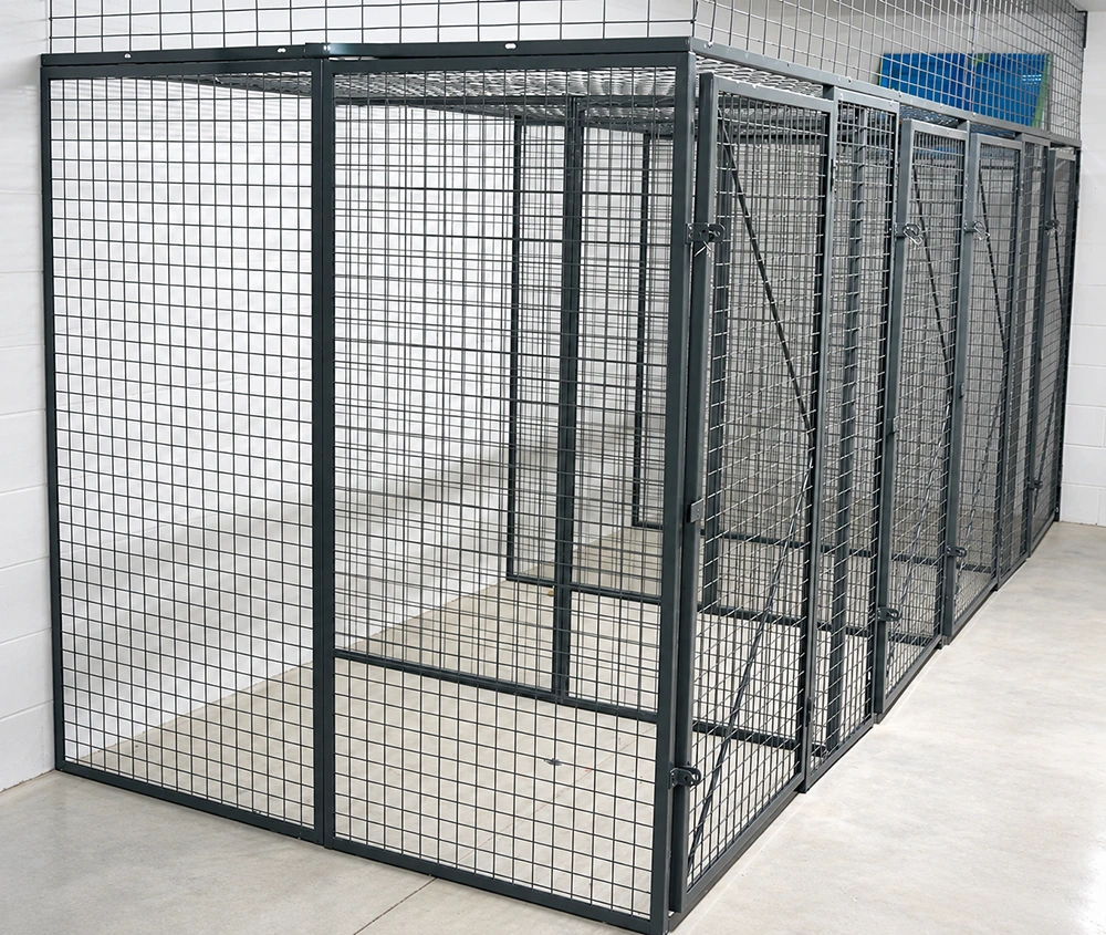 Black welded wire mesh storage cages with hinged doors and tubular steel frames for modular indoor partitioning.